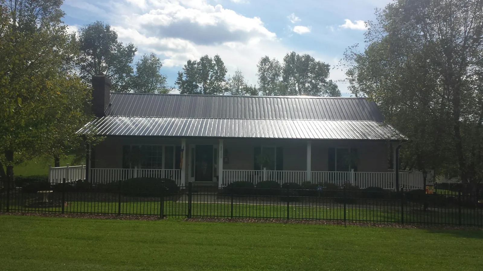 Gray metal roof on a brick ranch with a full width front porch — Gutter Guard Installation work by our crew in Cedar Crest