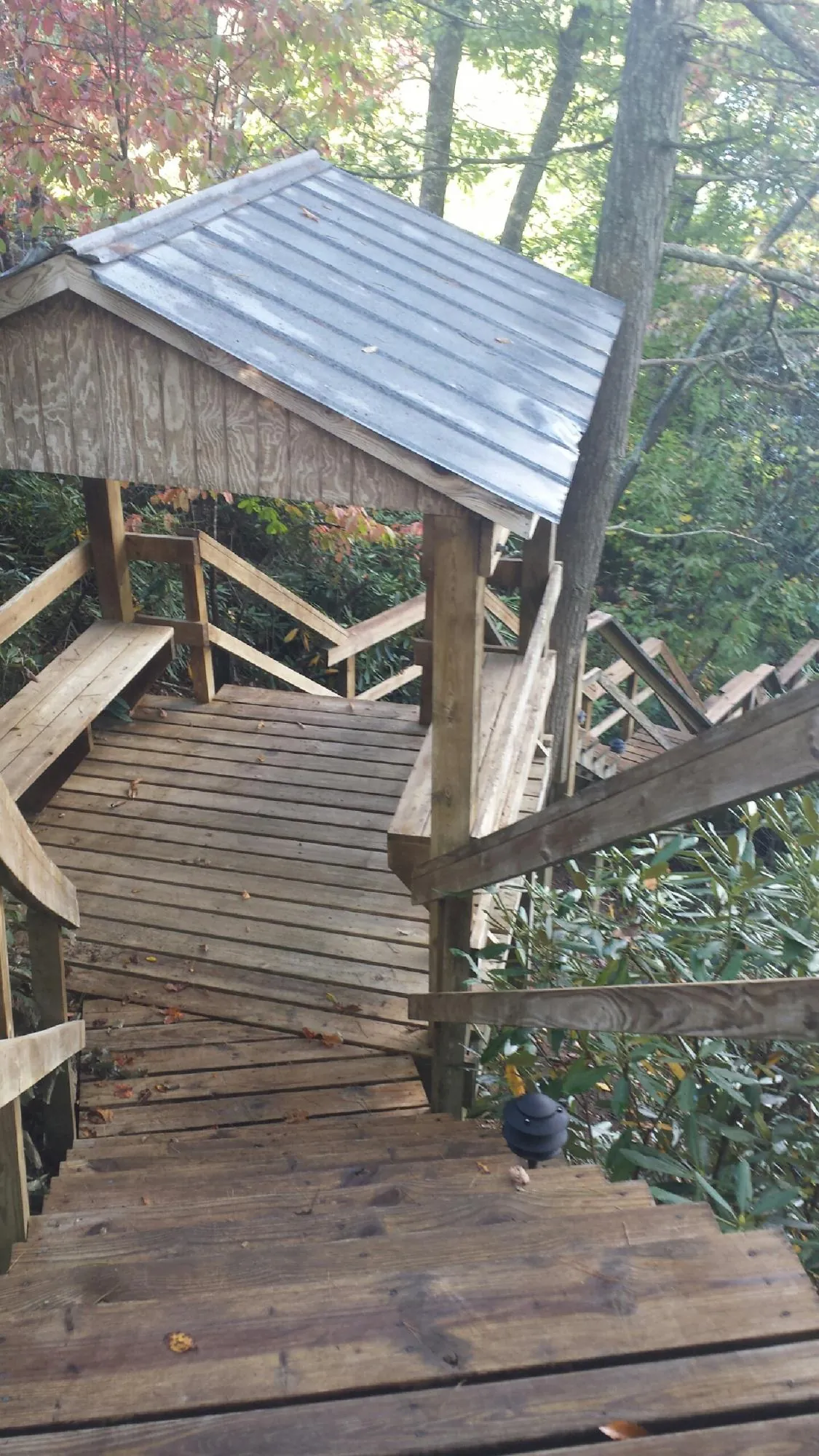 Metal roofed shelter over wooden steps on a wooded walkway — Skylight Repair & Installation work by our crew in Cedar Crest