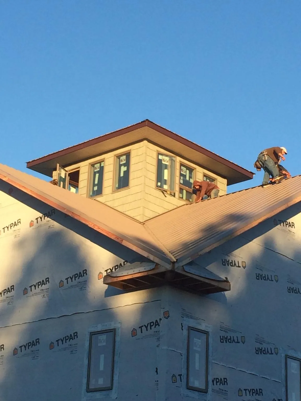 Roofers working around a rooftop cupola on a new metal roof at sunset — Roof Waterproofing in Cedar Crest by Roofing Brothers